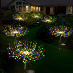Colorful outdoor string lights arranged in a circular pattern on a lawn in front of a house.