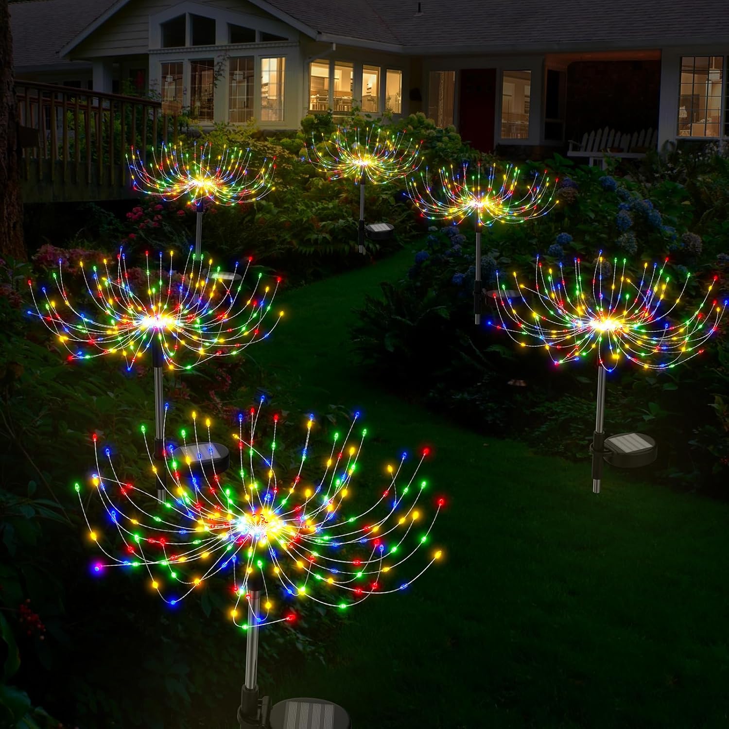 Colorful outdoor string lights arranged in a circular pattern on a lawn in front of a house.